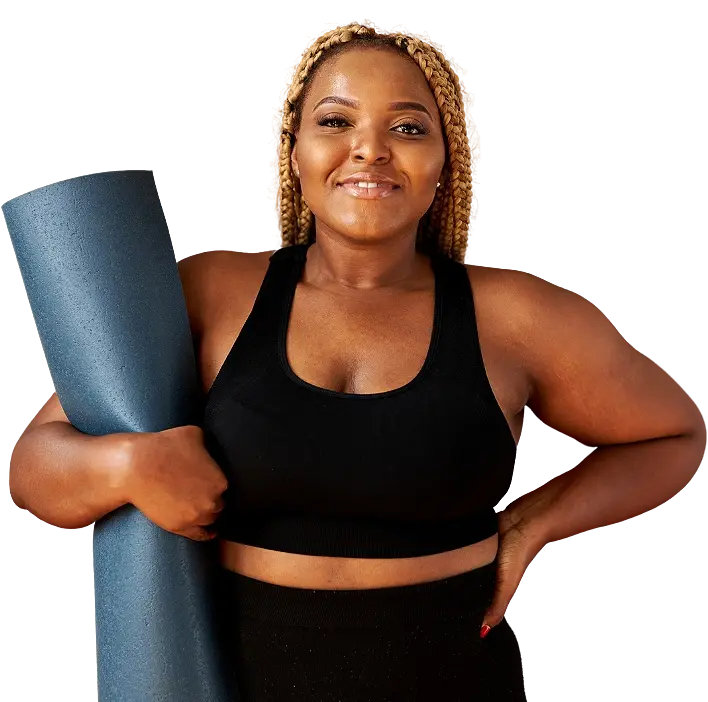 A smiling woman holding a rolled-up yoga mat under her arm