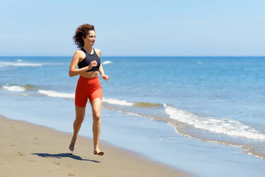 59873552_happy-young-woman-training-on-sandy-beach-and-running